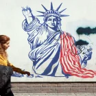 Una mujer camina junto a un mural antiestadounidense cerca de la antigua Embajada de EE. UU. en Teherán.