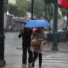 Personas se movilizan bajo la lluvia que sorprendió a la ciudad en horas de la tarde.