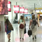 Personal aeroportuario y viajeros se movilizan hacia la terminal aérea con documentación de vuelo en medio de las restricciones nocturnas.