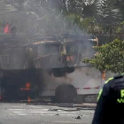 Un integrante de la Policía de Colombia observa un vehículo afectado por una explosión este 24 de abril de 2026, en Cali (Colombia).