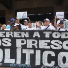 Personas sostienen carteles como parte de una manifestación para denunciar la situación de los presos políticos en cárceles de Venezuela este lunes, en Caracas (Venezuela).