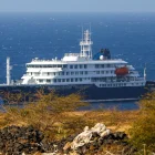 El crucero holandés MV Hondius (atrás), anclado frente a la costa de la ciudad de Praia en la isla de Santiago, Cabo Verde, este lunes 4 de mayo de 2026,