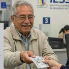 Referencial. Un adulto mayor recibe su pensión en una ventanilla del IESS.