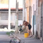 Una mujer limpió la vereda en el sector donde fue abandonado el cadáver de un hombre, frente a una escuela, en el Guasmo Sur de Guayaquil.