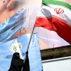 Una mujer con velo sostiene la bandera nacional de Irán frente a una enorme valla publicitaria antiestadounidense en Teherán, Irán, el 11 de mayo de 2026.