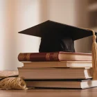 Referencial. El birrete universitario sobre libros simboliza la culminación académica y el registro oficial de títulos en Ecuador.