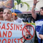 Cubanos en el exilio sostienen un cartel que dice "Asesinos y terroristas" mientras celebran el Día de la República de Cuba en Miami, Florida, EE. UU., el 20 de mayo de 2026.