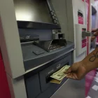 Personas usan los cajeros automáicos para retirar o depositar dinero.