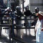 Una mujer aimara camina frente a un grupo de policías durante una protesta por quinta semana consecutiva este 1 de junio de 2026, en La Paz (Bolivia).