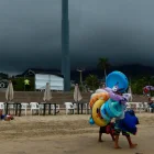 Fotografía referencial, vendedores caminan en una playa.