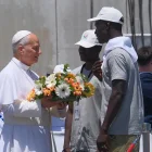 El papa León XIV recibe flores de dos voluntarios para protagonizar una ofrenda floral en el mar en recuerdo de los migrantes muertos.