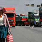 Una mujer quechua camina frente a vehículos de una caravana de transportistas para exigir el levante de los bloqueos de carreteras este lunes, en Cochabamba (Bolivia).