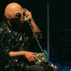 La obra transcurre en un espacio íntimo que remite a una sala. Desde allí, el intérprete comparte pensamientos, canciones y acciones performáticas