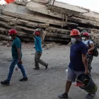 Personas caminan frente a los escombros de un edificio tras los sismos en La Guaira, Venezuela.