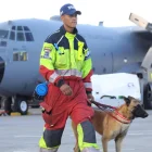 Aquí tienes un pie de foto breve, objetivo y neutral que complementa el contexto:

Un bombero camina con un perro de rescate en la pista de Latacunga antes de viajar a Venezuela este jueves.