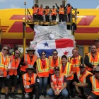 Personal de carga junto a un envío con la bandera de Panamá en un avión de DHL