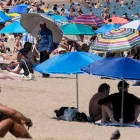 Turistas buscan sombra bajo sombrillas en playas europeas durante la ola de calor.