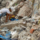 Una persona busca entre los escombros de edificios destruidos por terremotos en Caraballeda.