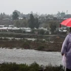 Una persona observa el caudal del Río Mapocho al costado de un campamento en riesgo de inundación en la comuna de Talagante (Chile)