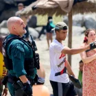 Un agente coordina con vecinos en la playa de Ceuta durante la llegada masiva de migrantes desde Marruecos.