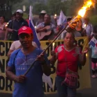 Campesinos sostienen banderas y velas en una vigilia en rechazo al decreto ejecutivo que ordena la clausura de los cementerios comunitarios.