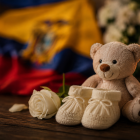Un osito, unos zapatitos de bebé y una vela encendida simbolizan el duelo perinatal y la memoria de una vida que no llegó a nacer.