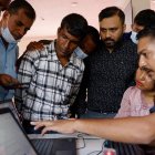 Familiares se reúnen alrededor de un agente de policía para consultar una base de datos informática con información sobre las víctimas de la masiva riada.