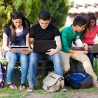 Group of teenagers social networking using several tech devices in high school