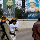 Personas armadas pasan junto a pinturas que representan a líderes hutíes fallecidos, expuestas en una valla en Saná, Yemen, el 7 de septiembre de 2026.