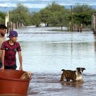 Personas cruzan en medio de una inundación causada por el paso de la tormenta tropical Polo en Guaymas al sur de Sonora (México).