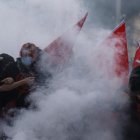 Estudiantes de secundaria permanecen en medio de gases lacrimógenos mientras estallan enfrentamientos entre estudiantes y la policía antidisturbios.