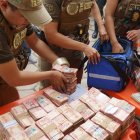 Integrantes de la Fuerza Especial de Lucha Contra el Crimen (FELCC) de Bolivia cuentan billetes que fueron encontrados en una ambulancia.