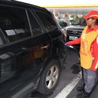 Una trabajadora de una gasolinera despacha el combustible para un carro.